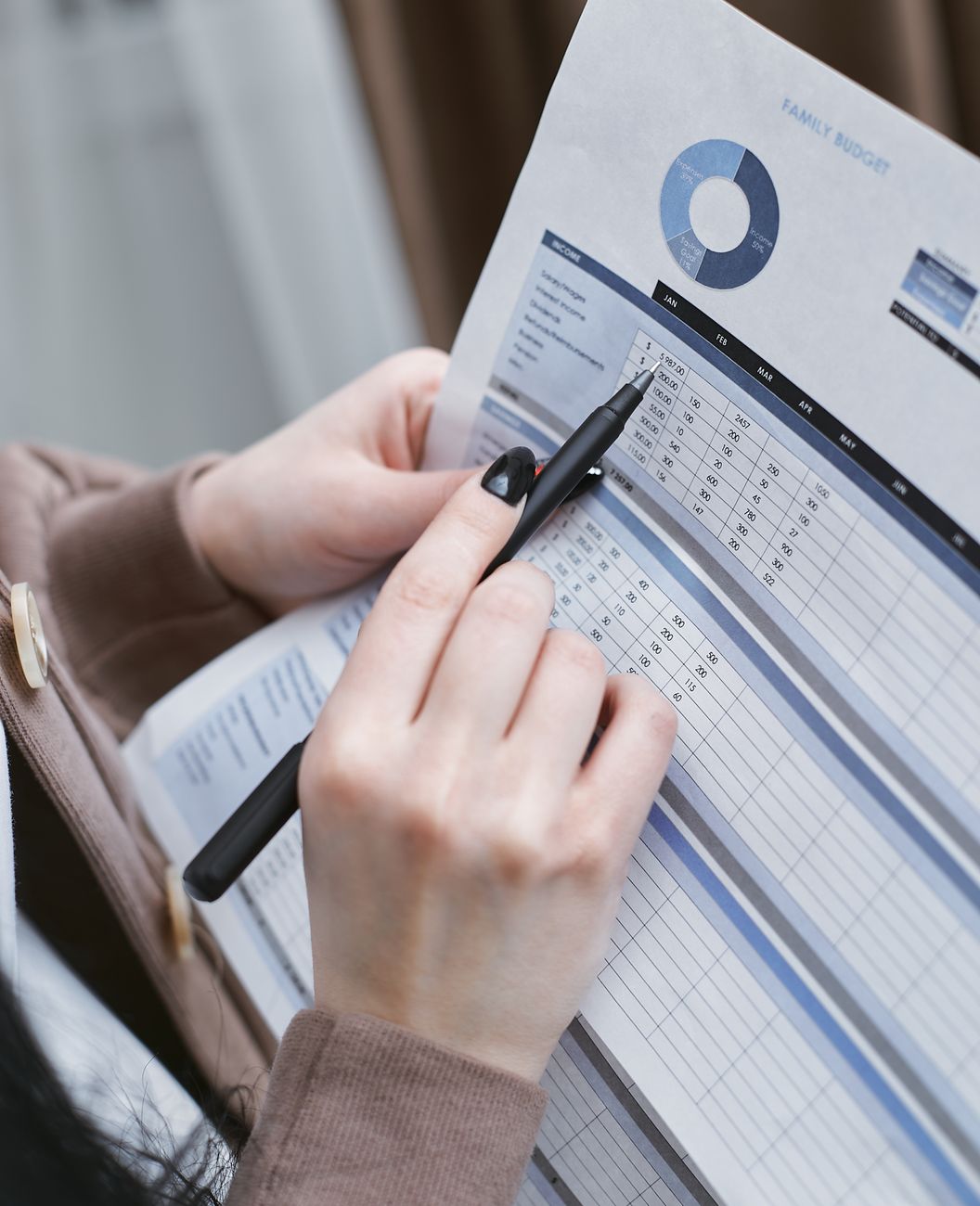 a person holding black pen writing on a white paper